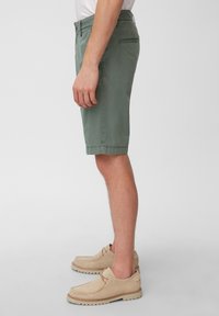 Khaki vihreät shortsit, joissa on sivutaskut, puuvillakangasta ja säädettävä vyötärö. Yhdistetty vaaleanbeigeihin liukuviin kenkiin.