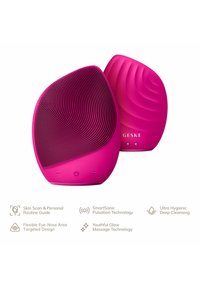 Dispositif de nettoyage facial rose avec un devant texturé et un dos lisse, comportant des boutons et le nom de marque. Conçu pour la pulsation sonique et l'hygiène.