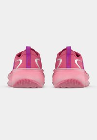 Pink athletic shoes with a smooth texture, rounded sole, contrasting purple hardware, and white logo accents on the back and sides.