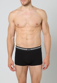 Boxers de algodão pretos com uma faixa elástica às riscas e logo da marca. O design é ajustado ao corpo e tem uma textura suave.