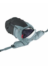 Blauer und schwarzer Rucksack mit mehreren Fächern, Reißverschlüssen und einem eingerollten Gegenstand darin. Verfügt über verstellbare Träger und verstärkten Stoff.