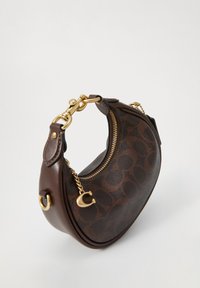 Petit sac à main en cuir marron foncé en forme de croissant avec fermeture éclair, chaîne et quincaillerie dorée, présentant un motif circulaire subtil sur le corps principal.