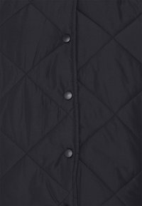 Quilted black vest featuring diamond pattern, front snap buttons, and a smooth texture. Lightweight design suitable for layering.
