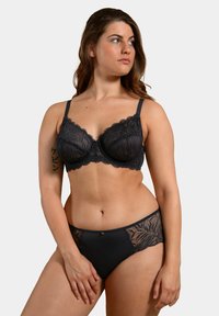 Soutien-gorge en dentelle noire avec armatures et bords festonnés, associé à un slip noir avec des accents en dentelle. Les deux articles mettent en avant des motifsintriqués.