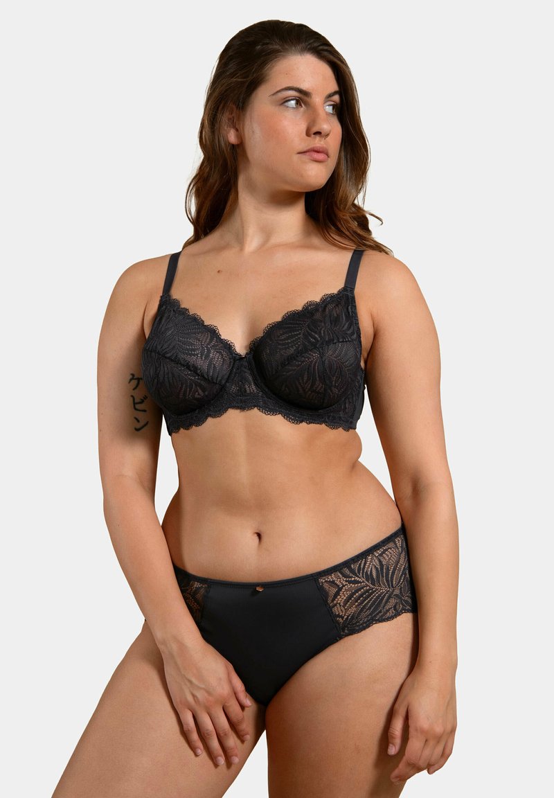 Soutien-gorge en dentelle noire avec armatures et bords festonnés, associé à un slip noir avec des accents en dentelle. Les deux articles mettent en avant des motifsintriqués.