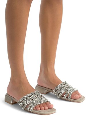 Infradito beige con una toma testurizzata e glitterata adornata da strass. Il tacco è basso e a forma di blocco, offrendo stabilità.