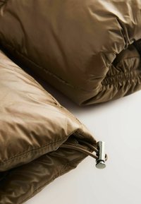 Oliven grøn pufferjakke med en glat, skinnende tekstur. Har samlede elastiske manchetter og en sølvfarvet justerbar toggle i kanten.