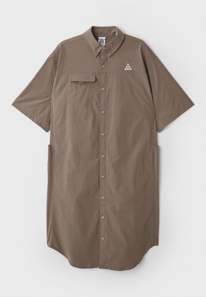 Bruine korte mouwen shirtjurk met een kraag, knopen aan de voorkant, een enkele borstzak en een logodetail op de bovenste linkerkant van de borst.