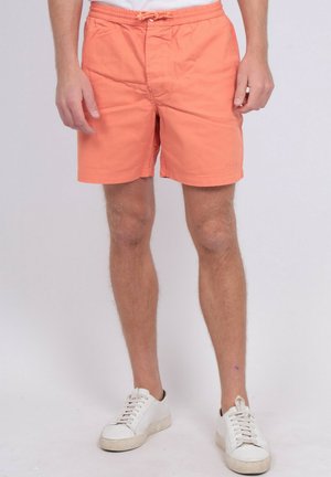 Shorts de bain pêche clair avec une taille élastique et un cordon de serrage, présentant une texture lisse et un branding subtil sur l'ourlet.