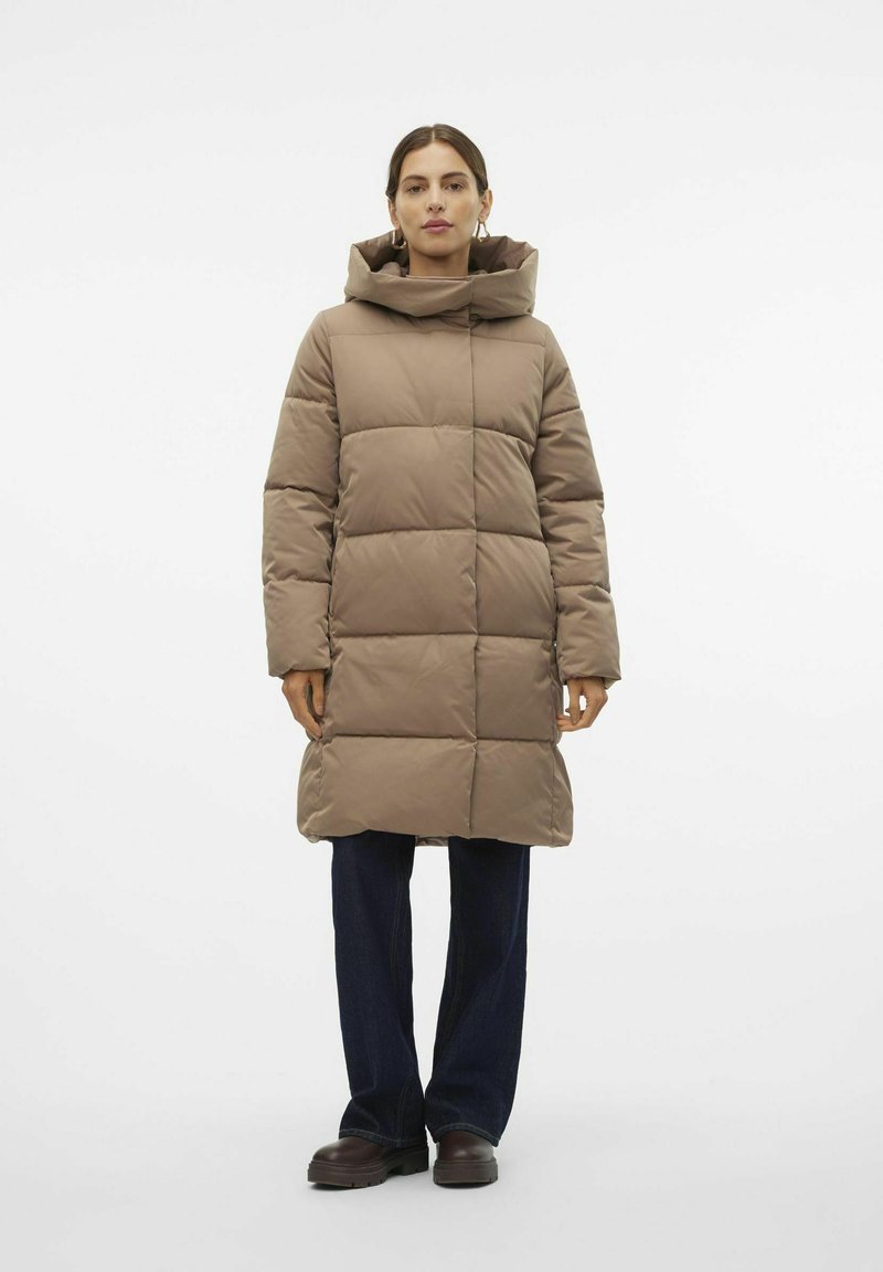 Abrigo puffer marrón claro con cuello alto y diseño acolchado, que presenta un corte recto, mangas largas y un dobladillo a la altura de la rodilla. Estilo casual.