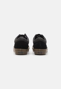 Sorte ruskind- og kanvas sneakers med en tan gummisål, der har en polstret krave og tekstureret bagside. Logo synligt på hælen.