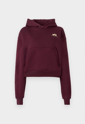 Sweat à capuche court bordeaux avec poche avant, manches longues et petit logo jaune Alpha Industries sur le haut de la poitrine gauche.