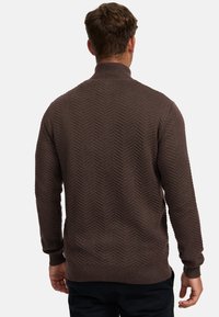 Brauner, gestrickter Pullover mit hohem Kragen, versehen mit einem strukturierten Fischgrätmuster sowie gerippten Bündchen an Ärmeln und Saum.