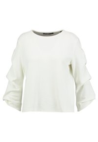 Vit texturerad blus med lösa trekvartsärmar som har samlade, lager av tygdetaljer.