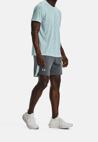 Light blue textured short-sleeve shirt paired with gray athletic shorts featuring a logo. White sneakers complete the sporty outfit.