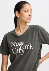 Dark gray cotton T-shirt featuring "New York City" text in contrasting white. V-neck design with short sleeves and a relaxed fit.