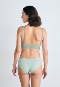 Mintgrön lingeriset som innehåller en bh med nätaccent och justerbara band, tillsammans med matchande högmidjade trosor med spetsdetaljer.