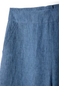 Falda azul de lino con una cintura alta y un bolsillo lateral, mostrando la textura del tejido y los detalles de las costuras.