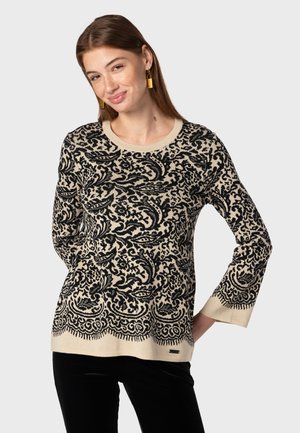 Pull en tricot beige avec un motif paisley noir complexe, col rond et manches longues. Présente un ourlet festonné et une étiquette en bas.
