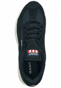 Black athletic shoe featuring a mesh upper, suede accents, flat laces, and a logo patch with red, white, and blue stripes on the tongue.