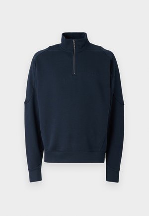 Felpa con zip di colore navy, dotata di un colletto alto, polsini a costine e una texture morbida. Logo discreto sul petto. Design classico e casual.