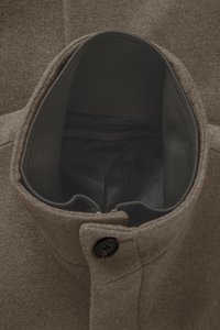 Manteau en laine marron à la texture douce, présentant un col intérieur côtelé, une fermeture à un bouton, et une doublure noire à l'intérieur du col.
