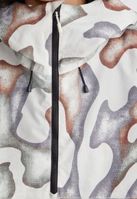 Hoodie-Jacke in einem Camouflage-Muster mit Grautönen, Braun und Creme. Verfügt über einen durchgehenden Reißverschluss und verstellbare Kordeln an der Kapuze.