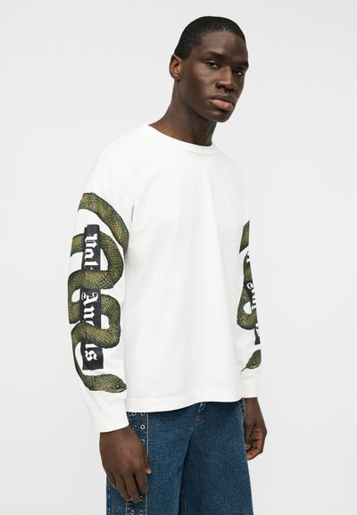 Λευκό μακρυμάνικο μπλουζάκι με πράσινα γραφικά φιδιού και κείμενο στα μανίκια. Κατασκευασμένο από βαμβάκι, με άνετη εφαρμογή και στρογγυλή λαιμόκοψη.
