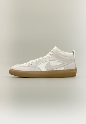 Balti ir šviesiai rožiniai zomšiniai Nike aukštakulniai sportbačiai su guminiu padu ir įmonės logotipu "swoosh" šone, matomi iš išorinės pusės.