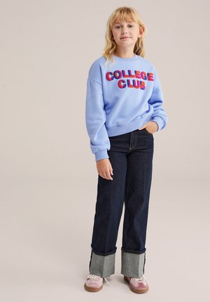 Ljusblå sweatshirt med "COLLEGE CLUB" i flerfärgad fluff. Bärs med högmidjade mörk denimjeans med grå manschett. Avslappnad skor.