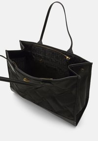 Czarna torba tote wykonana z pikowanej nylonu, z dwiema mocnymi rączkami, wewnętrzną kieszenią na zamek oraz złotym akcentem z logo.