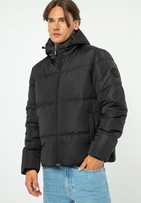 Černá péřová bunda s vysok�ým límcem a zipovým zapínáním. Obsahuje prošívané panely a logo na rukávu. Hladký materiál a běžný střih.