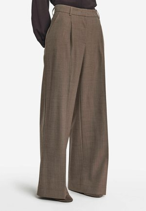 Pantaloni larghi in un ricco tessuto marrone con un motivo delicato, dotati di pieghe frontali, tasche e una finitura liscia e texturizzata.