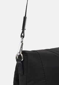 Black padded shoulder bag strap with a silver metal clip and leather connector. Smooth texture with a rectangular shape.