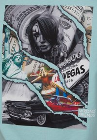 Grafika obsahující roztrhnutou koláž dolarových bankovek, ženské tváře, Sochy svobody, vintage černého auta a znamení "Vítejte v Las Vegas".
