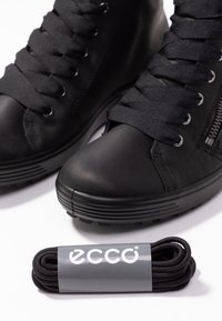 Sorte høje sneakers med tekstureret læder, snørebåndsdesign, rund tå og lynlås på siden, ledsaget af sorte snørebånd i en grå label.