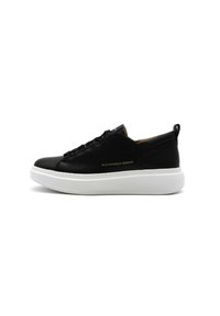 Sneaker nera in pelle con soletta piatta bianca, caratterizzata da una parte superiore testurizzata e un discreto marchio dorato.
