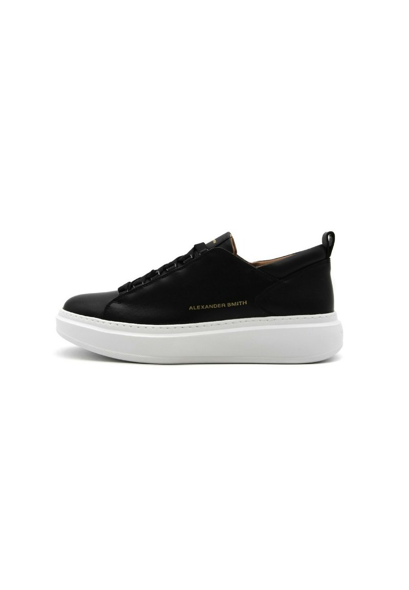 Sneaker nera in pelle con soletta piatta bianca, caratterizzata da una parte superiore testurizzata e un discreto marchio dorato.