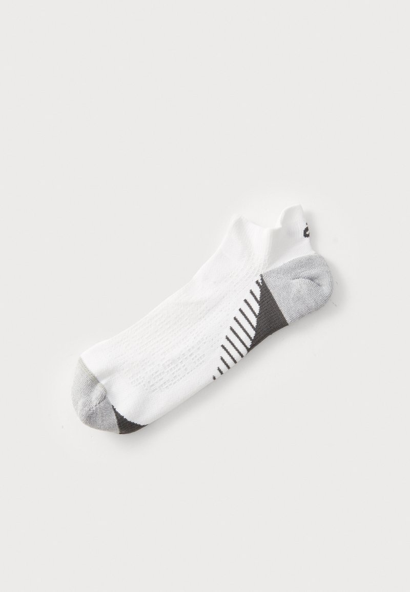 Tief ausgeschnittene weiße Socke mit grauem Zeh, Ferse und schwarzen diagonalen Streifen auf dem Fußgewölbe, auf einem schlichten weißen Hintergrund präsentiert.