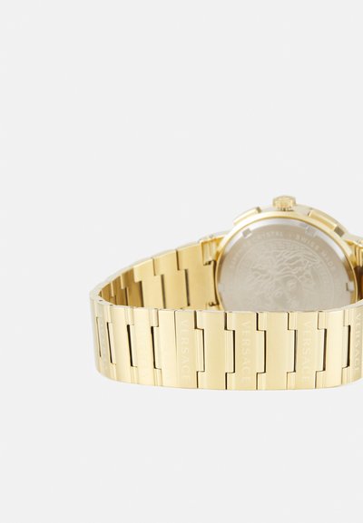 Zelta tonis nerūsējošā tērauda pulkstenis ar saites aproci. Iespējas apaļš korpuss un gluda, iegravēta aizmugure. Zīmola nosaukums redzams uz aproces saitēm.