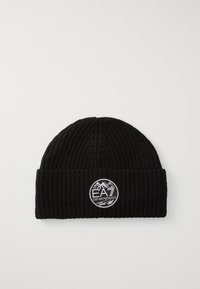 Crna rebrasta pletena kapa s preklopom koja sadrži okruglu oznaku s logotipom koji prikazuje planine i natpis "EA7 Emporio Armani".