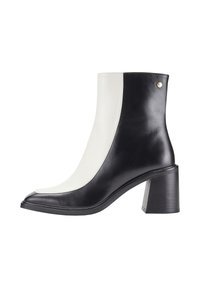 Bottines en cuir noir et blanc avec un bout carré, un talon carré et une texture lisse. Présente des détails de couture et un accent métallique.