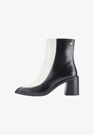 Bottines en cuir noir et blanc avec un bout carré, un talon carré et une texture lisse. Présente des détails de couture et un accent métallique.