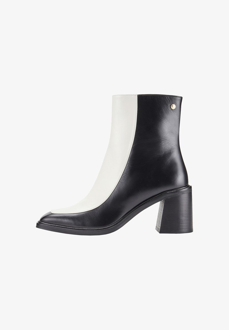 Bottines en cuir noir et blanc avec un bout carré, un talon carré et une texture lisse. Présente des détails de couture et un accent métallique.