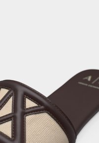 Σανδάλι με φερμουάρ, με σκούρο καφέ δέρμα και άνω μέρος από μπεζ ύφασμα με γεωμετρικό σχέδιο κοπής στη σόλα.