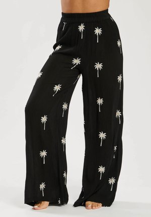 Pantalones anchos y negros hechos de una tela texturada con bordado de palmeras en blanco y plata en toda la prenda. Cintura elástica para mayor comodidad.