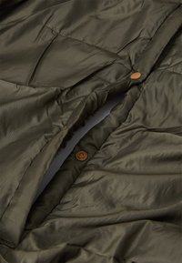 Olivenfarvet pufferjakke med en glat, blank overflade. Har brune trykknapper og stitched paneler, der fremhæver det isolerede design.