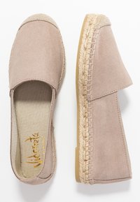 Beżowe zamszowe espadryle z teksturową jutikową podeszwą. Otwarty tył z haftowanym wykończeniem. Miękka tkanina wyścielająca wnętrze.