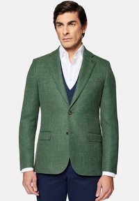 Zielona, teksturowana marynarka z tkanej tkaniny, z zapięciem na dwa guziki, klapami i przednimi kieszeniami z klapą, w połączeniu z białą koszulą.