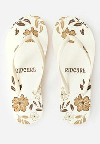 Tongs blanches avec des motifs floraux bruns, semelle texturée et brides beiges portant le nom de la marque "RIP CURL" imprimé en brun.